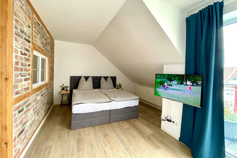 Schlafbereich mit Doppel-Boxspringbett und Ziegelwand